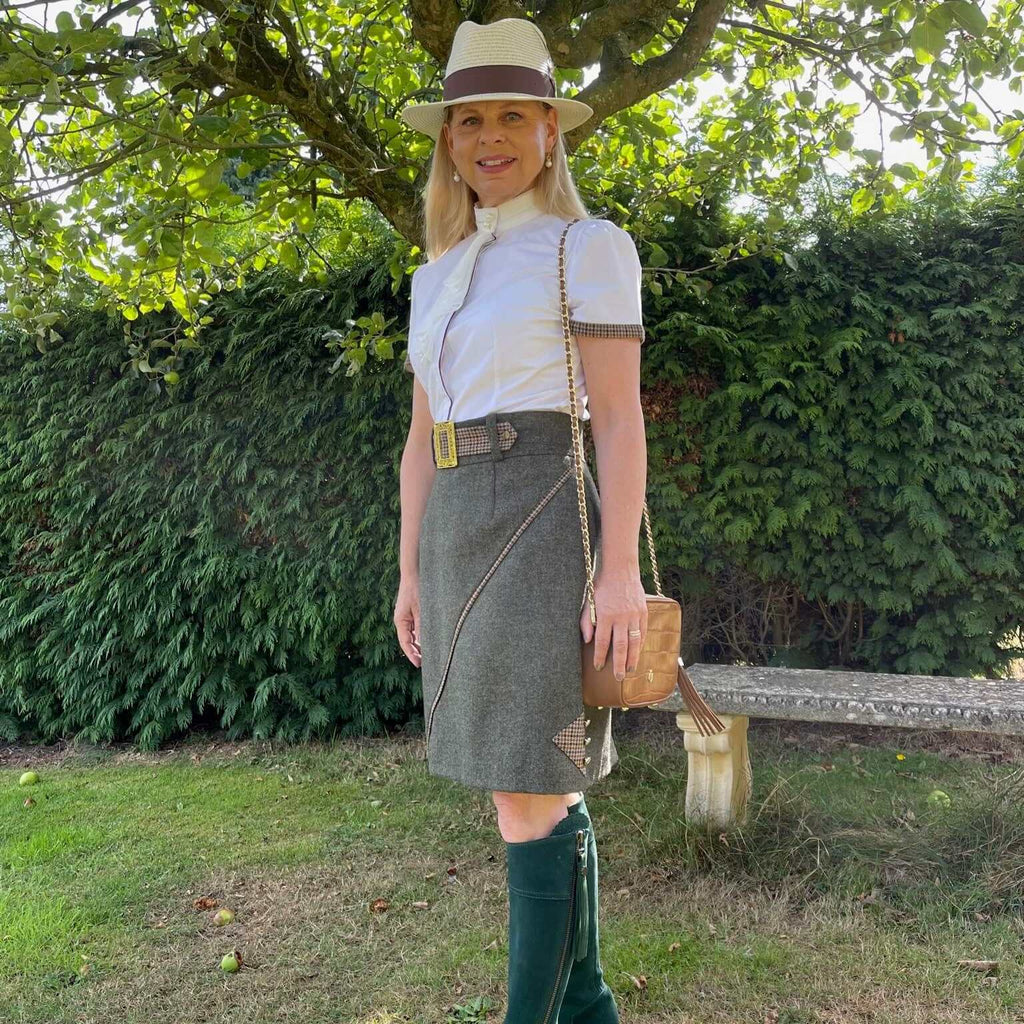 Lifestyle image of the Adderbury tweed skirt in Village Green, styled with long boots