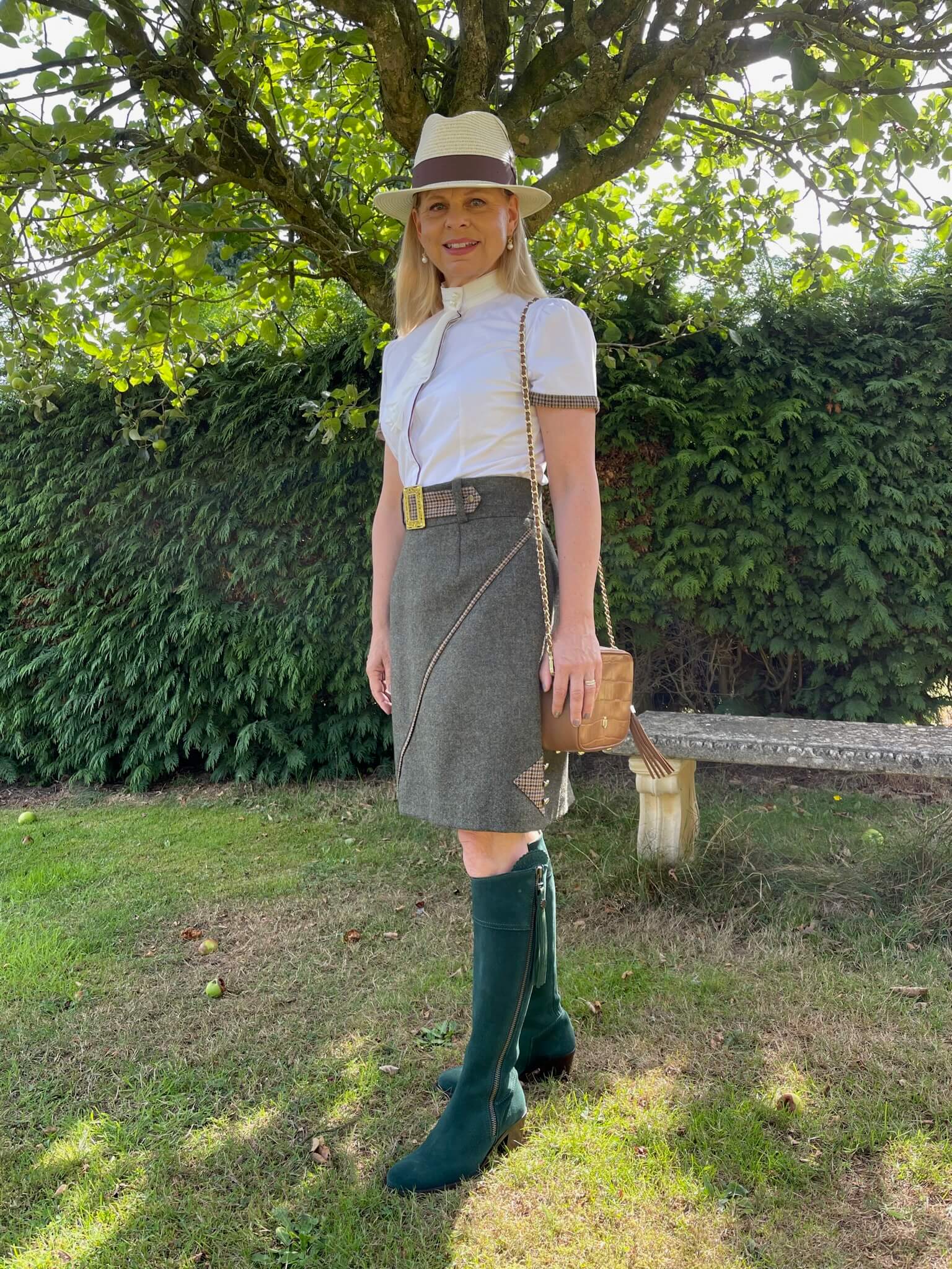 Lifestyle image of the Adderbury tweed skirt in Village Green, styled with long boots