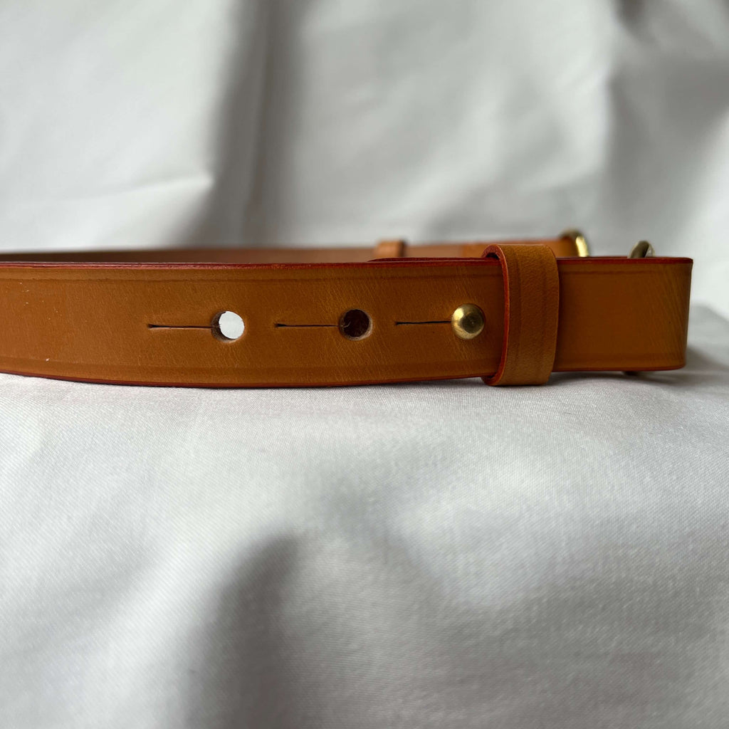 Side view of a tan bridle leather belt with side fastenings