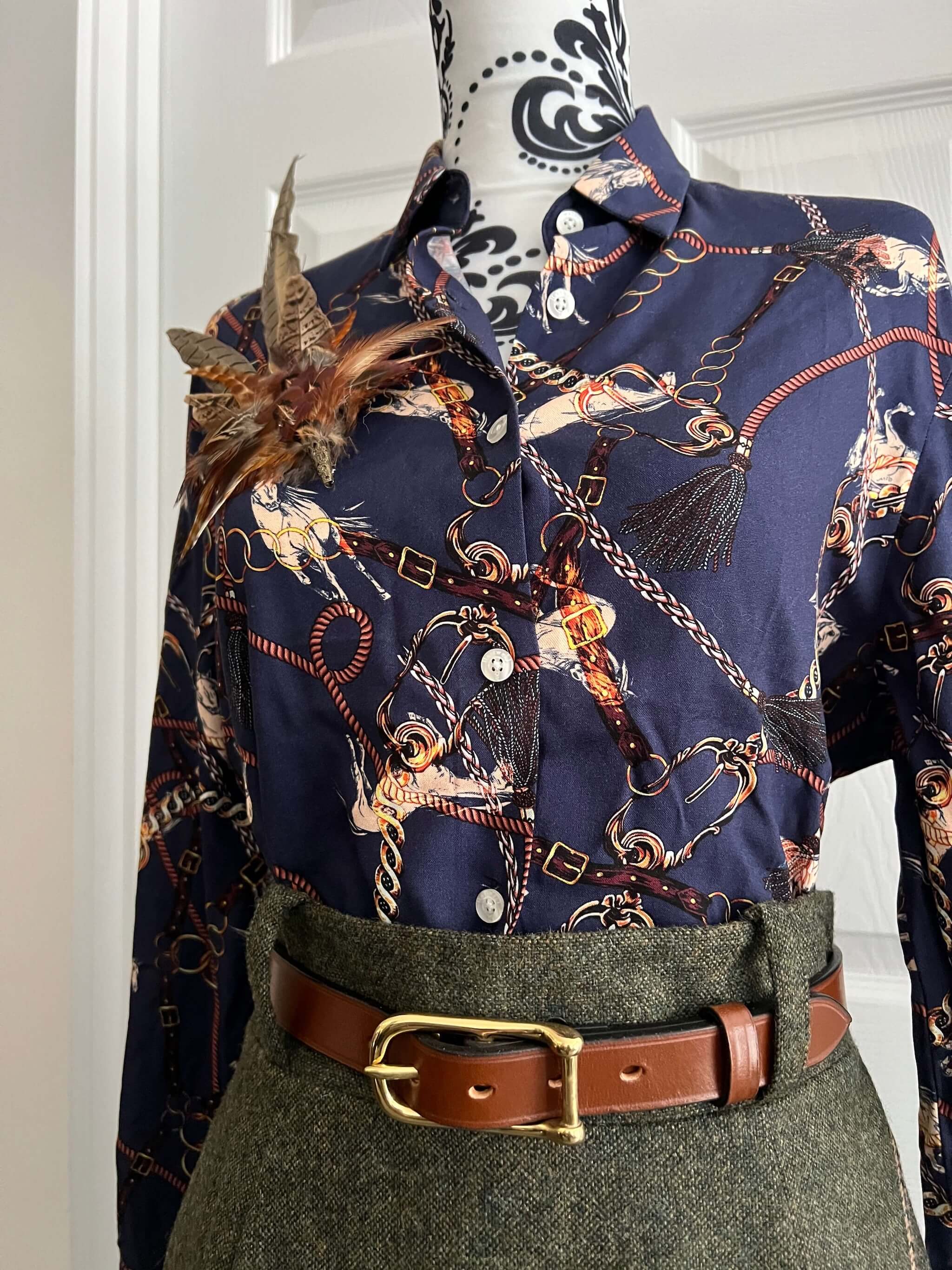 women's country clothing outfit featuring leather belt, feather hat pin and tweed skirt