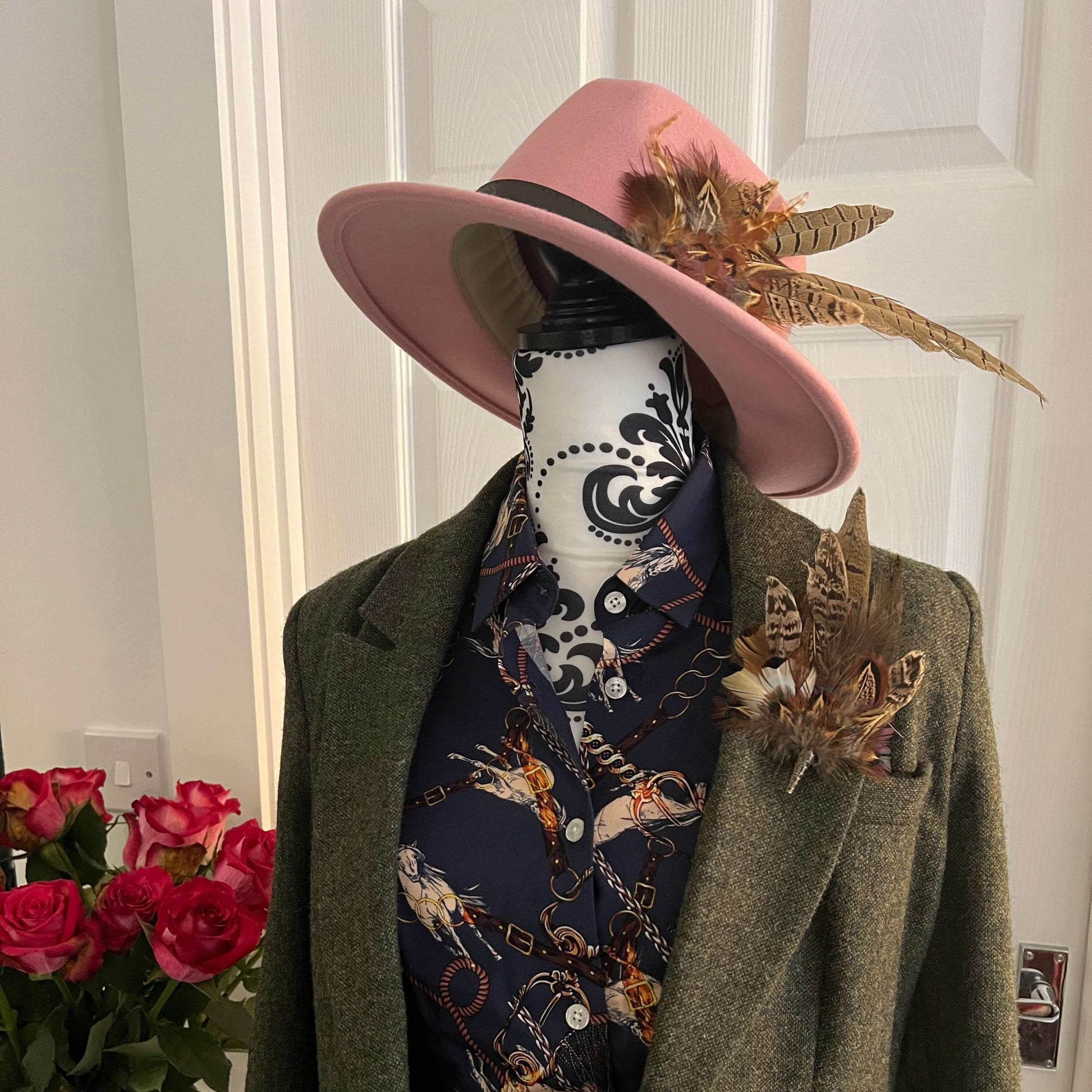 Mannequin dressed for jumps racing with a tweed jacket, feather hat pin, feather brooch pin, and blue equestrian shirt