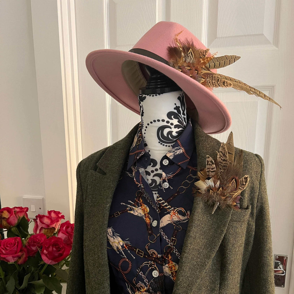 Mannequin dressed for jumps racing with a tweed jacket, feather hat pin, feather brooch pin, and blue equestrian shirt