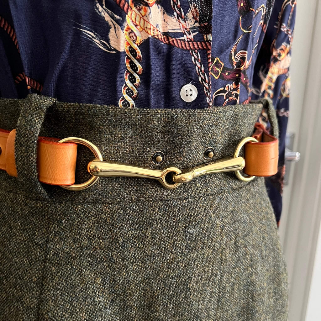 close-up of tan leather belt showing solid brass hardware