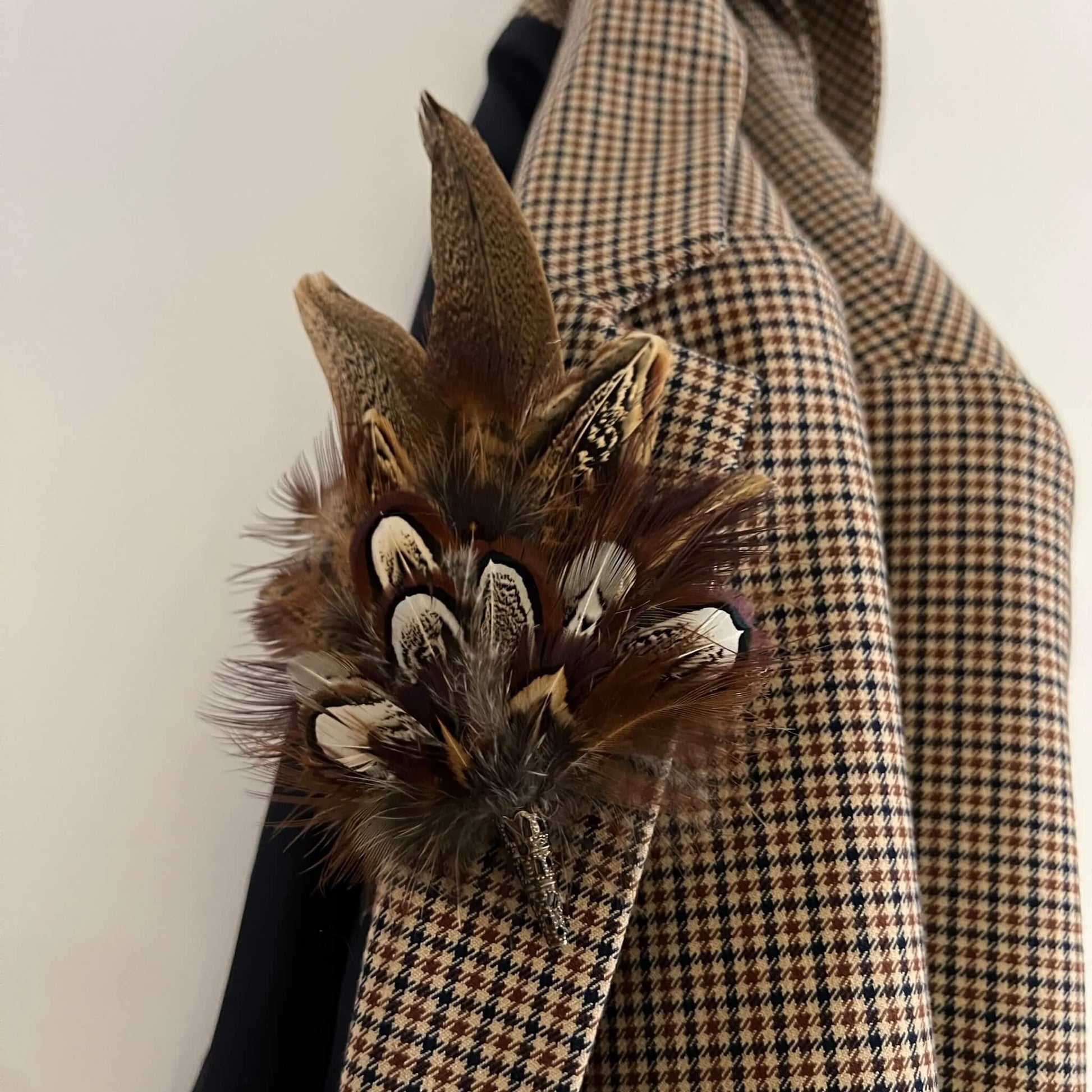 small feather brooch pin fastened to a check jacket